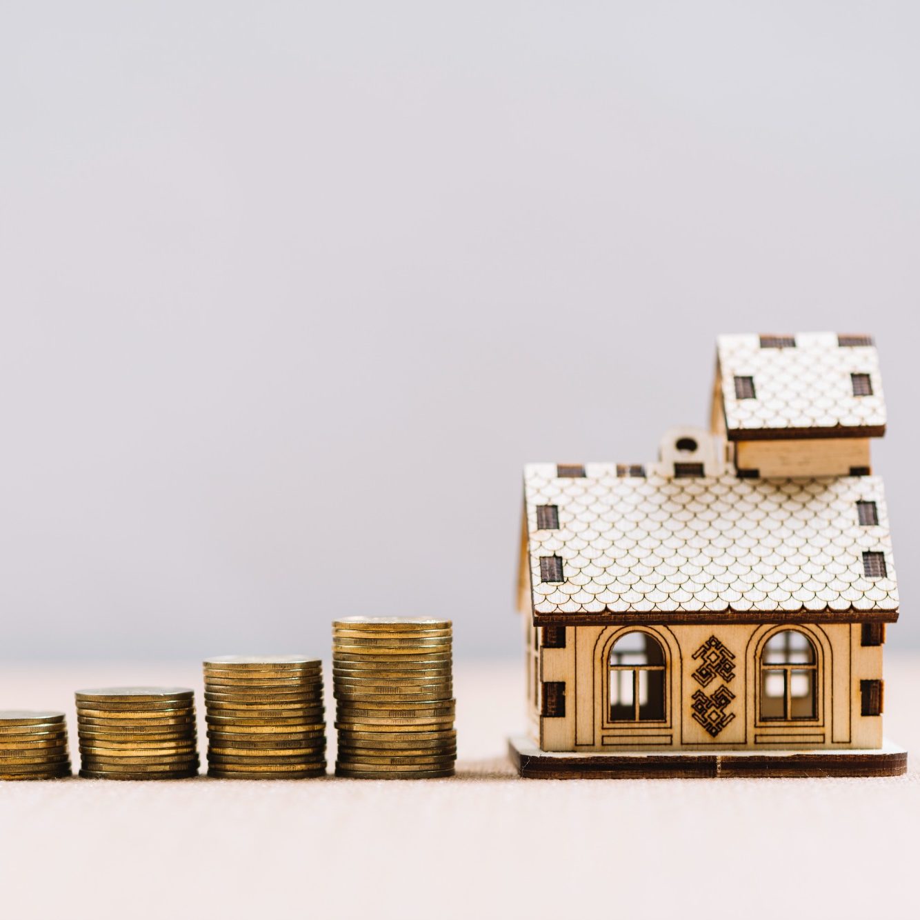 Investissement locatif rentable : maison miniature en bois et piles de pièces, accompagnement Loany