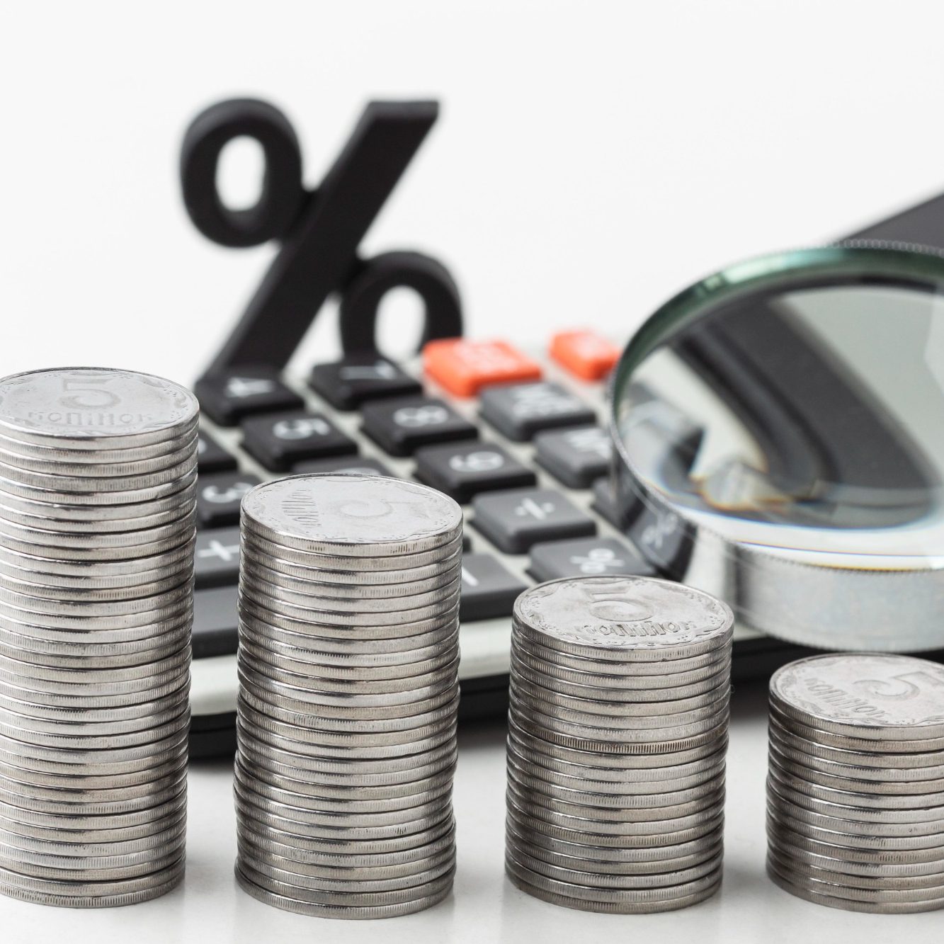 Illustration Loany : trois piles de pièces, calculatrice, loupe et pourcentage symbolisant le courtage en crédit immobilier